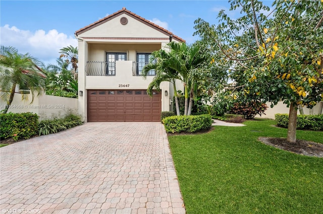 view of front of property featuring a balcony, a front yard, and a garage