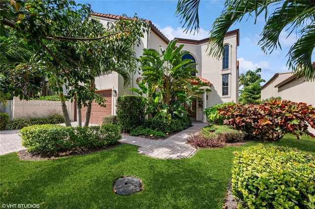 mediterranean / spanish-style home with a front yard and a garage