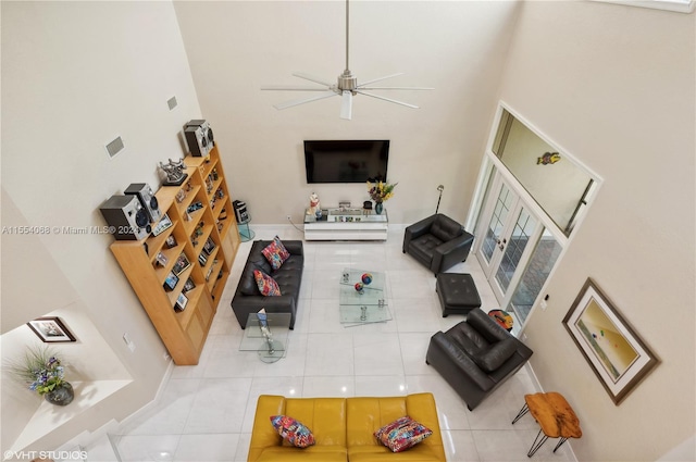 tiled living room with ceiling fan and a high ceiling