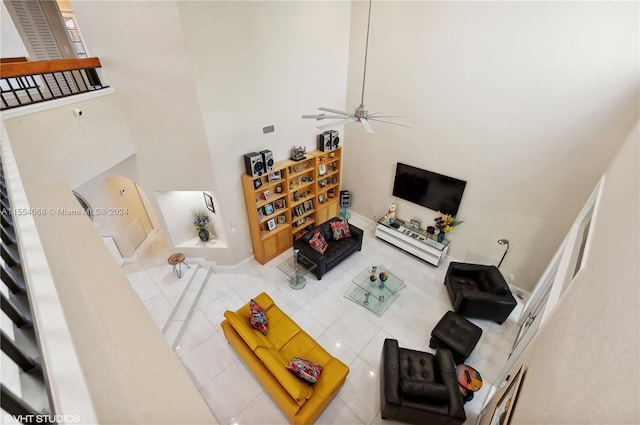 living room with ceiling fan, light tile floors, and a towering ceiling