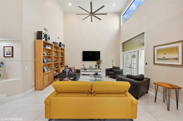 tiled living room with french doors, ceiling fan, and a high ceiling