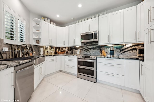 kitchen with white cabinets, dark stone countertops, backsplash, stainless steel appliances, and light tile flooring