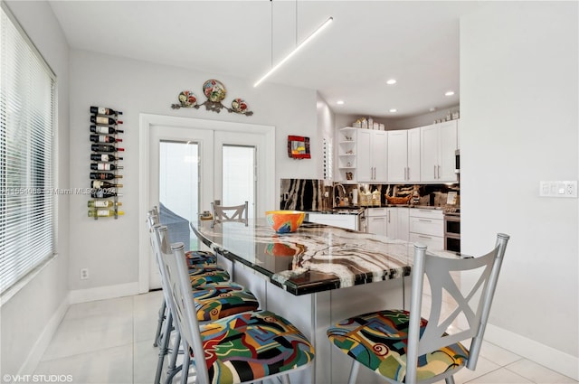 kitchen with backsplash, electric stove, light tile floors, white cabinets, and dark stone countertops