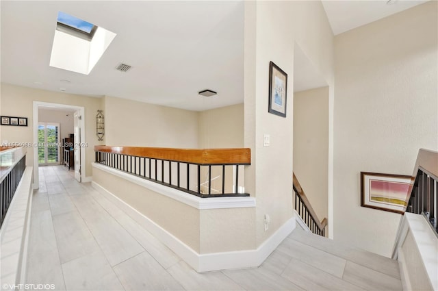 hall with light tile flooring and a skylight