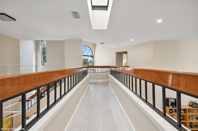 hall featuring light tile floors and a skylight