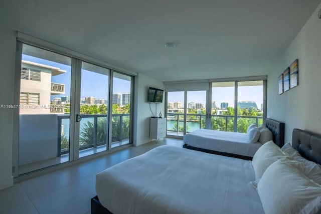 bedroom featuring light tile floors, a wall of windows, and a water view