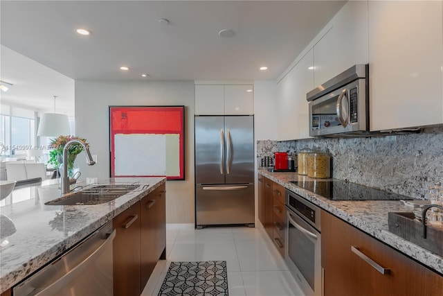 kitchen with light stone countertops, stainless steel appliances, light tile floors, white cabinets, and tasteful backsplash