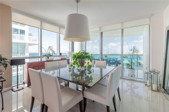 tiled dining area with floor to ceiling windows, a wealth of natural light, and a water view