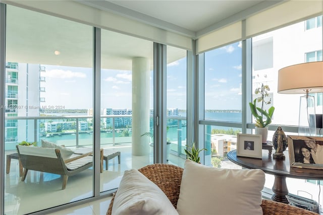 tiled living room featuring a water view and a wall of windows