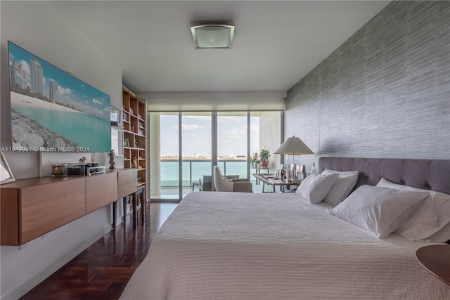 bedroom featuring access to outside, dark hardwood / wood-style flooring, and a water view