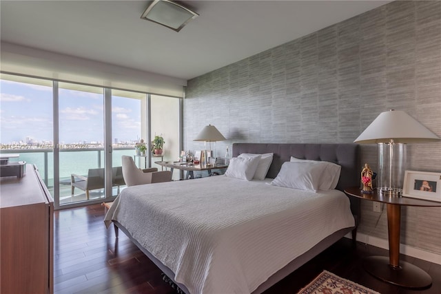 bedroom featuring a water view, access to exterior, and dark hardwood / wood-style flooring