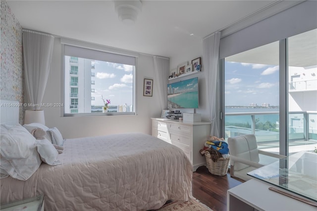 bedroom featuring dark hardwood / wood-style floors and a water view