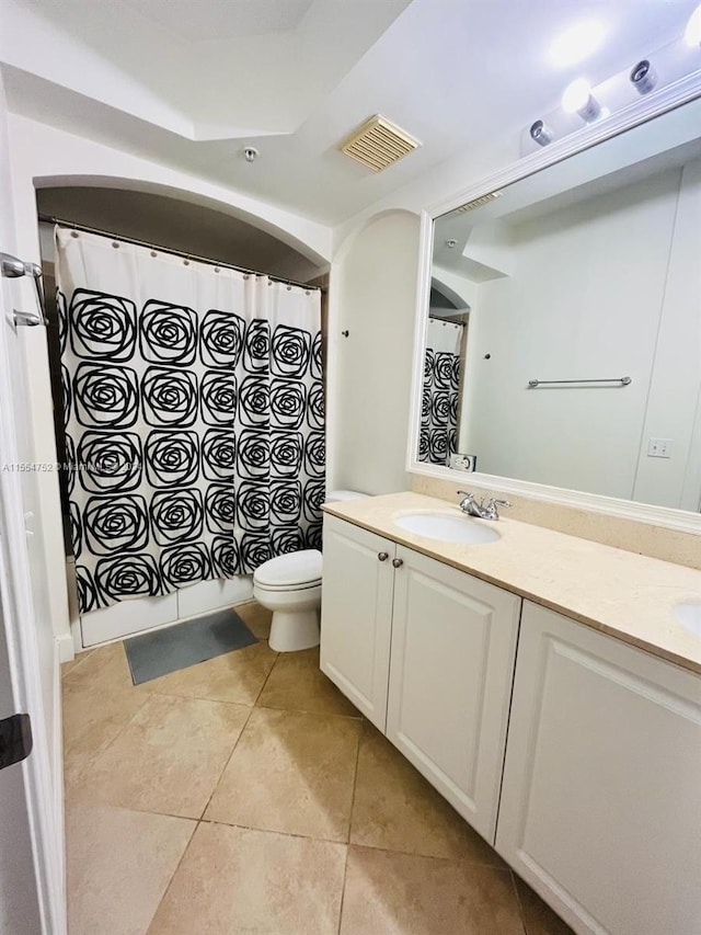 bathroom with tile flooring, double vanity, and toilet