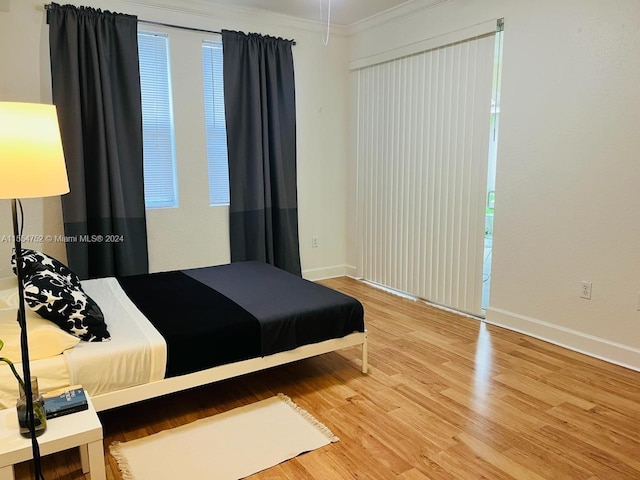 bedroom featuring crown molding, multiple windows, and light wood-type flooring