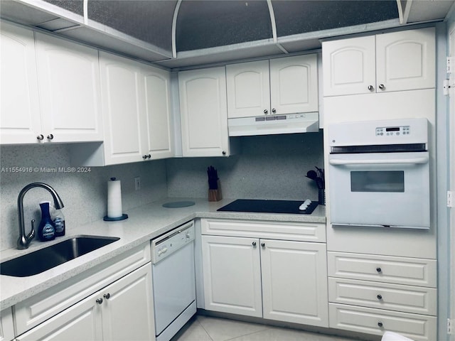 kitchen with white appliances, sink, light tile floors, white cabinets, and tasteful backsplash