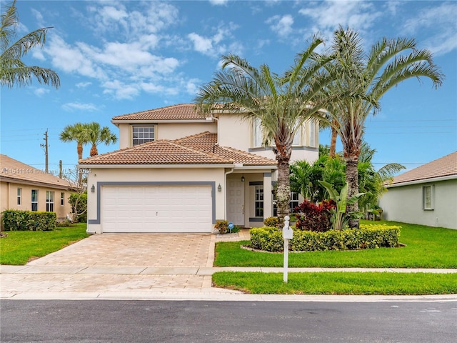 mediterranean / spanish house with a front lawn, decorative driveway, an attached garage, and stucco siding