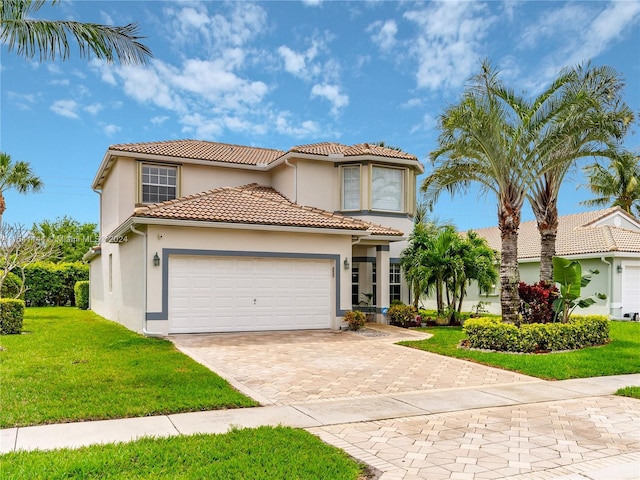 mediterranean / spanish-style home featuring a garage, a tiled roof, decorative driveway, a front lawn, and stucco siding