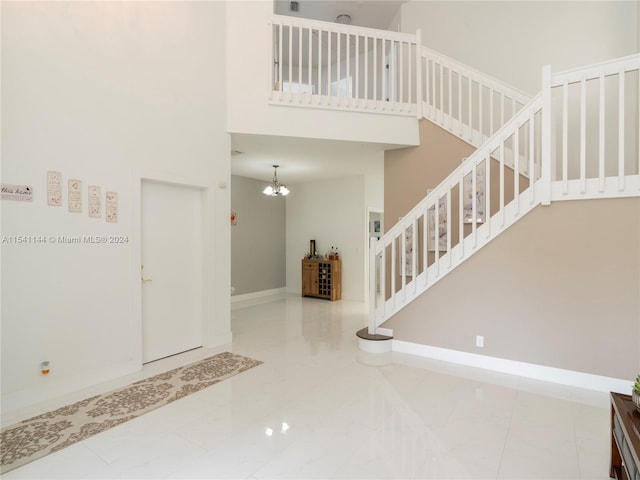 tiled entryway featuring an inviting chandelier and a towering ceiling