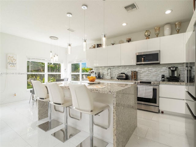 kitchen featuring visible vents, white cabinets, appliances with stainless steel finishes, light stone countertops, and backsplash