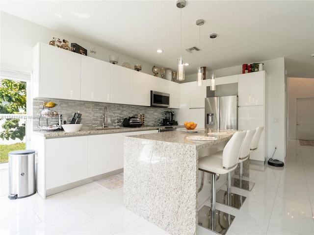 kitchen with tasteful backsplash, appliances with stainless steel finishes, pendant lighting, and a sink