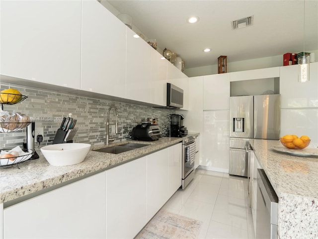 kitchen with a sink, white cabinets, appliances with stainless steel finishes, decorative backsplash, and modern cabinets