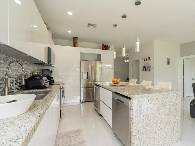 kitchen featuring stainless steel appliances, visible vents, a kitchen island, a sink, and modern cabinets