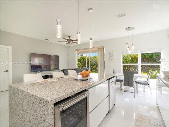 kitchen with wine cooler, visible vents, white cabinets, a center island, and decorative light fixtures