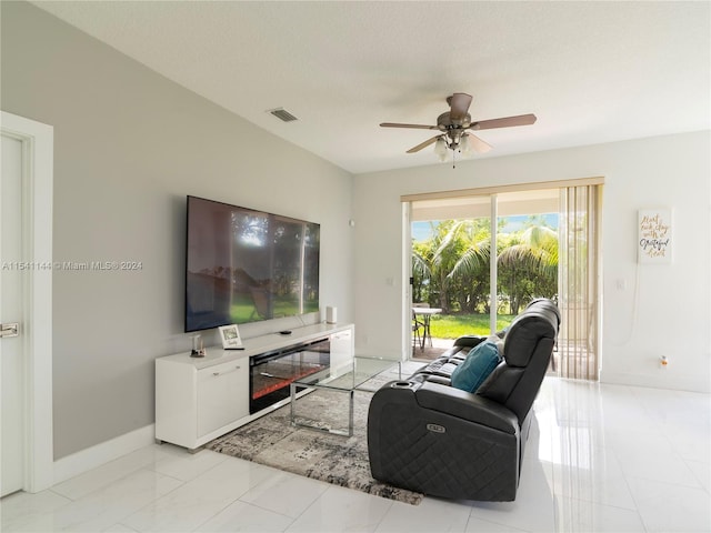 living area with ceiling fan, a textured ceiling, visible vents, and baseboards