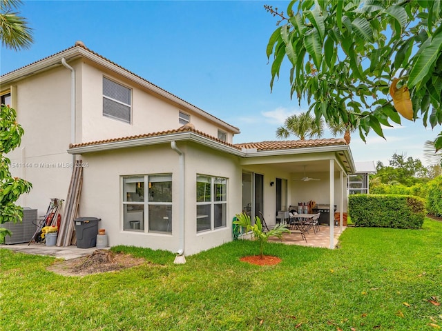 back of property with a patio area, a yard, a ceiling fan, and stucco siding