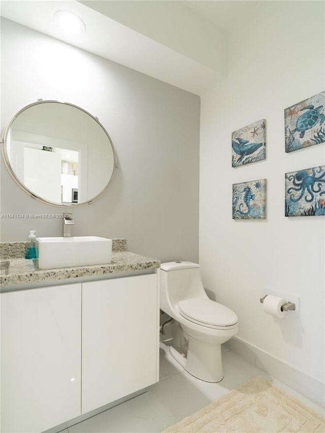 half bathroom with baseboards, vanity, and toilet