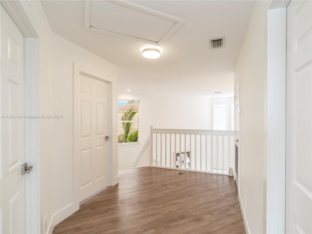 hall with visible vents, wood finished floors, and an upstairs landing