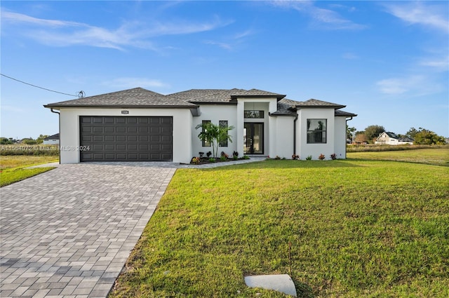 prairie-style house featuring an attached garage, stucco siding, decorative driveway, and a front yard