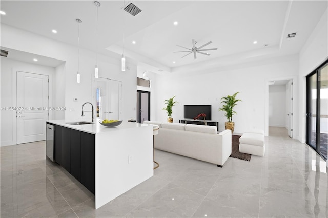 kitchen with a spacious island, a raised ceiling, decorative light fixtures, and a sink