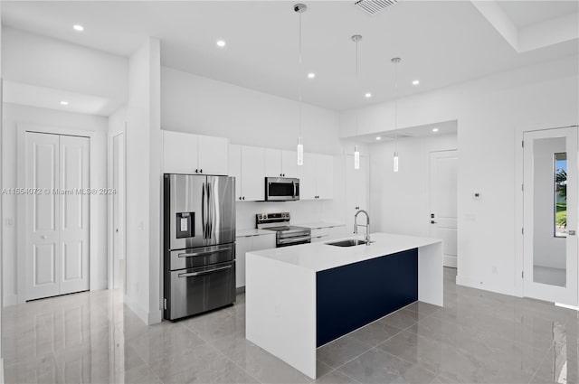 kitchen featuring a kitchen island with sink, a sink, light countertops, appliances with stainless steel finishes, and decorative light fixtures