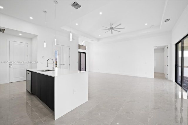 kitchen featuring a tray ceiling, hanging light fixtures, a sink, and a large island