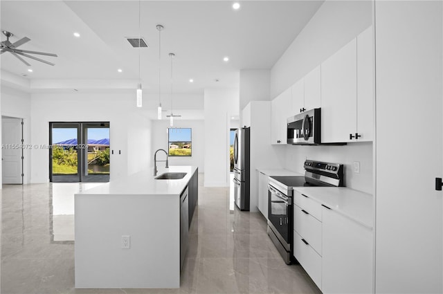 kitchen with a center island with sink, hanging light fixtures, stainless steel appliances, light countertops, and a sink