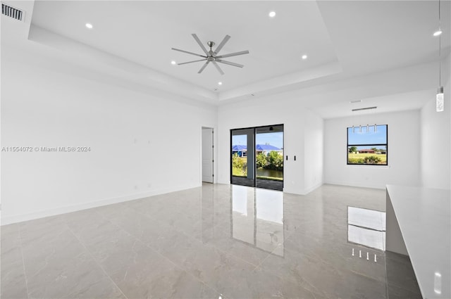 spare room featuring a tray ceiling, visible vents, and plenty of natural light