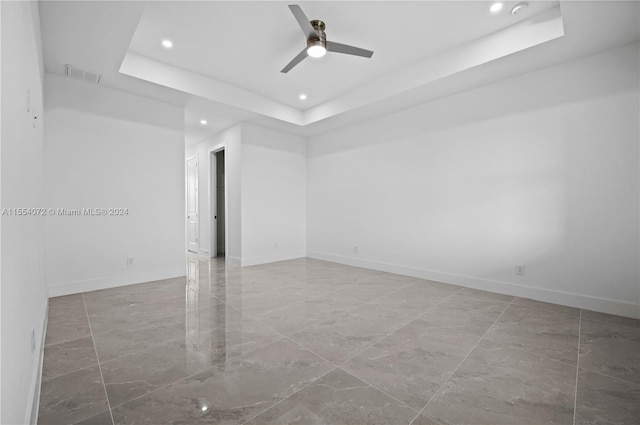 spare room featuring baseboards, visible vents, a raised ceiling, and recessed lighting