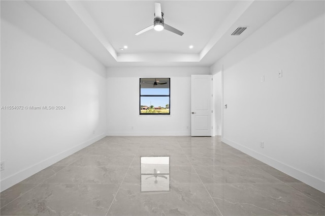 unfurnished room featuring visible vents, baseboards, a raised ceiling, and a ceiling fan