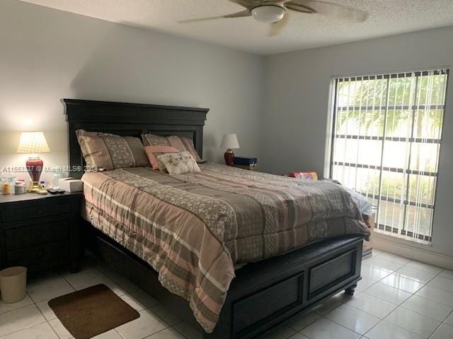 bedroom with a textured ceiling, ceiling fan, and light tile floors