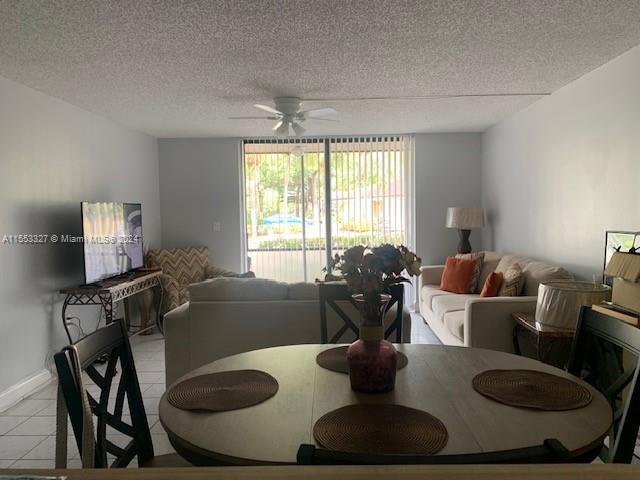 tiled dining room with a textured ceiling and ceiling fan