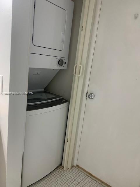 laundry area featuring light tile floors and stacked washing maching and dryer