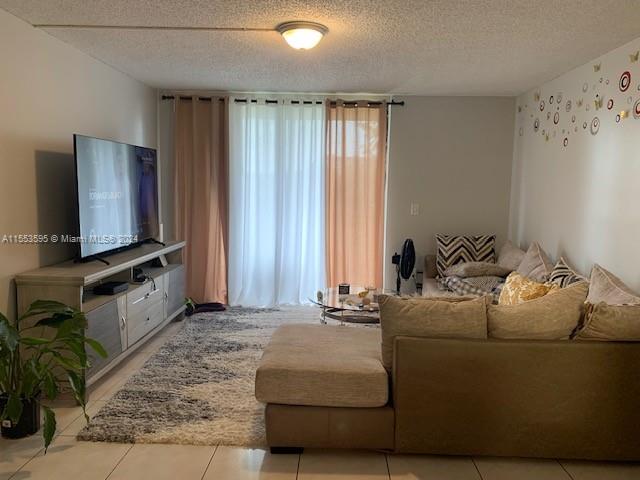 living room with a healthy amount of sunlight, light tile floors, and a textured ceiling