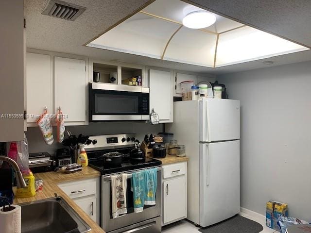 kitchen featuring stainless steel appliances, a textured ceiling, white cabinets, and sink