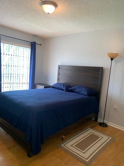 bedroom with a textured ceiling and light hardwood / wood-style flooring