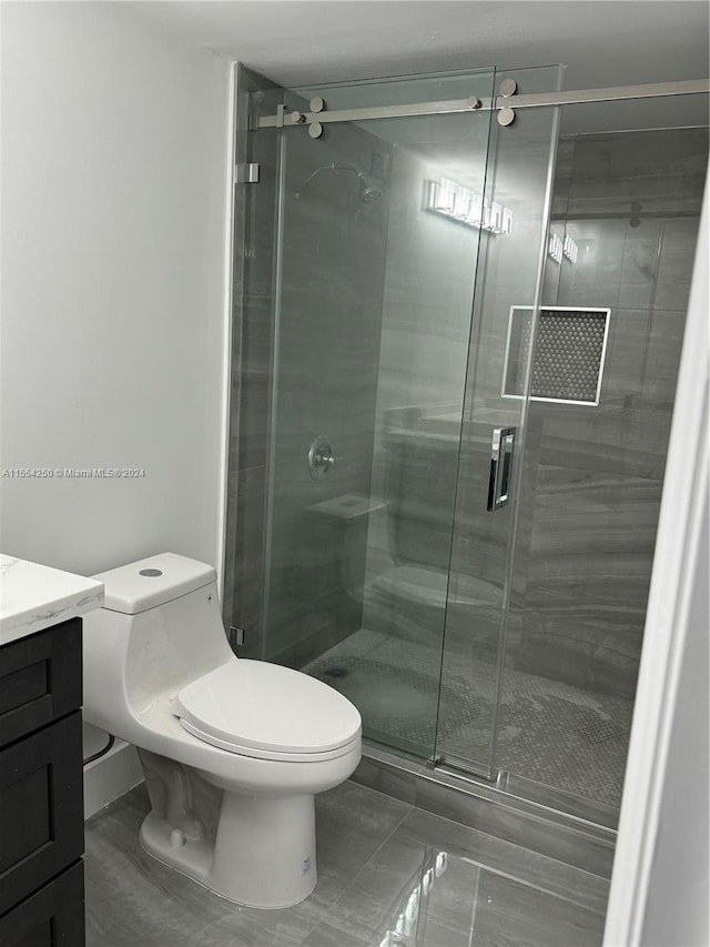 bathroom featuring a shower with door, toilet, and vanity