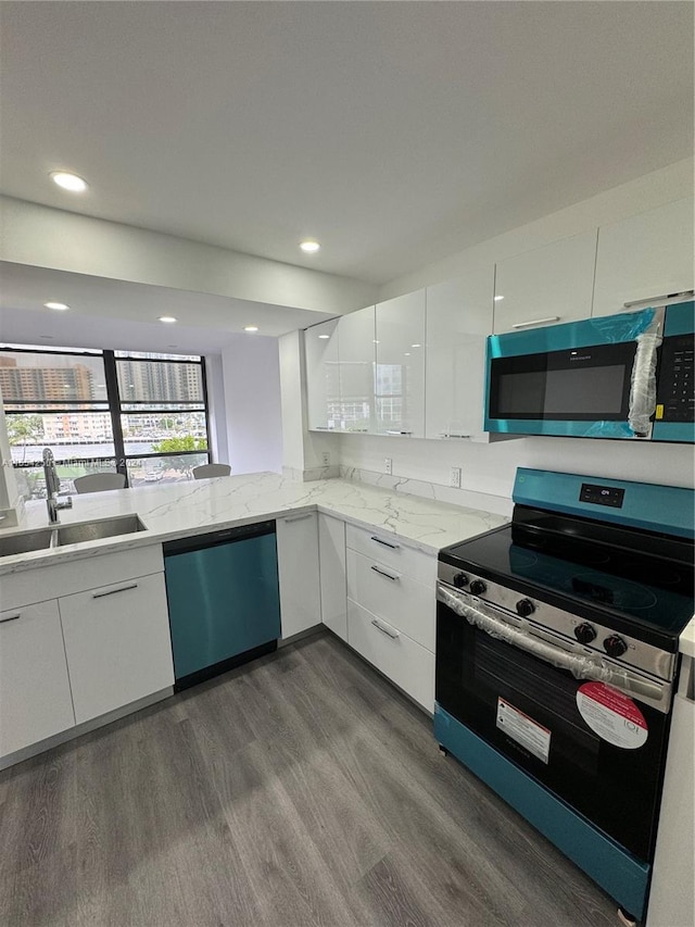 kitchen featuring dark wood-type flooring, white cabinets, stainless steel appliances, light stone countertops, and sink