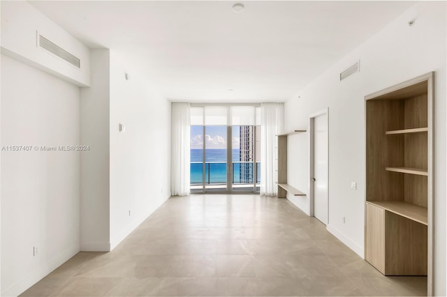 unfurnished room featuring a water view and expansive windows