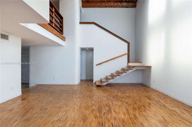 unfurnished living room featuring a towering ceiling and hardwood / wood-style floors