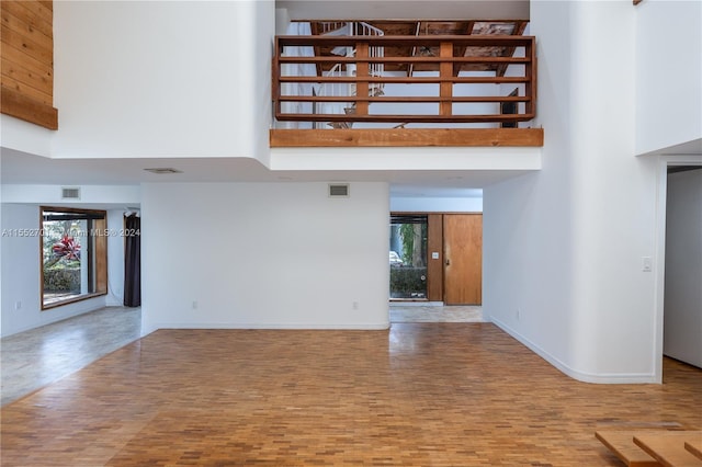 unfurnished living room featuring a towering ceiling and hardwood / wood-style flooring